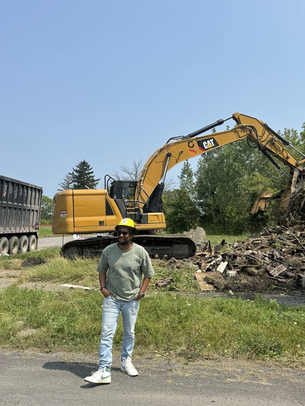 A Gayanga operator in front of a company CAT excavator loading debris