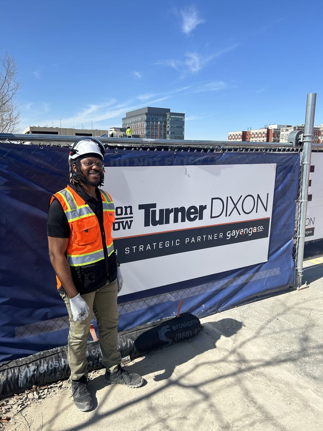 Gayanga worker in front of a Turner-Dixon strategic partner site banner on the Henry Ford Health expansion