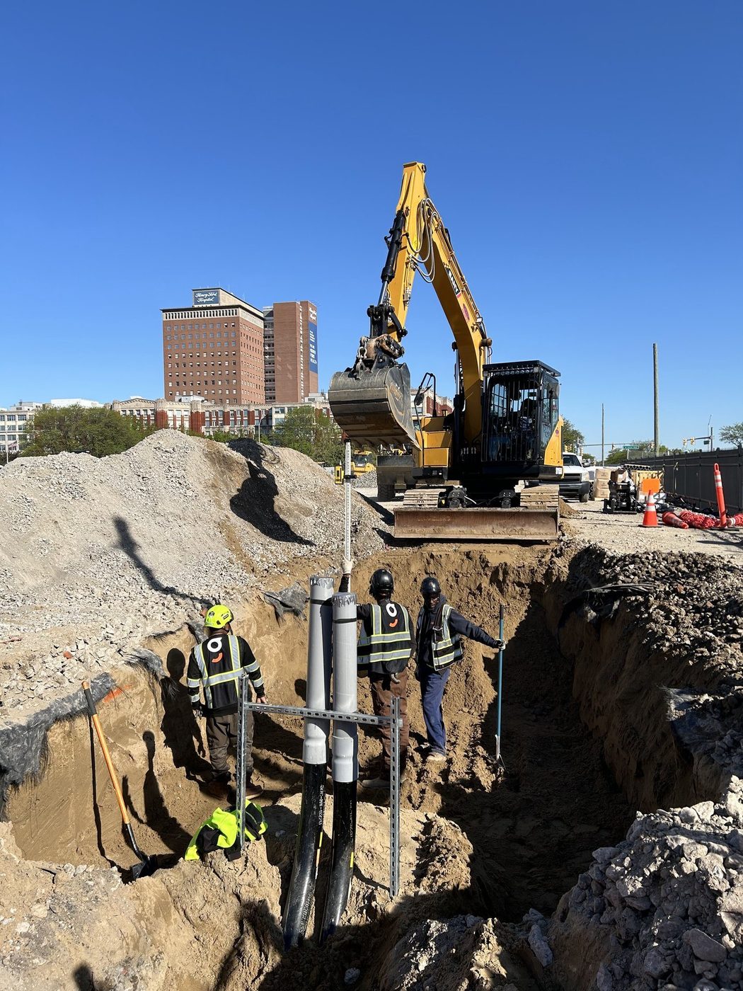 Gayanga laborers installing risers in a water main trench downtown, 2025